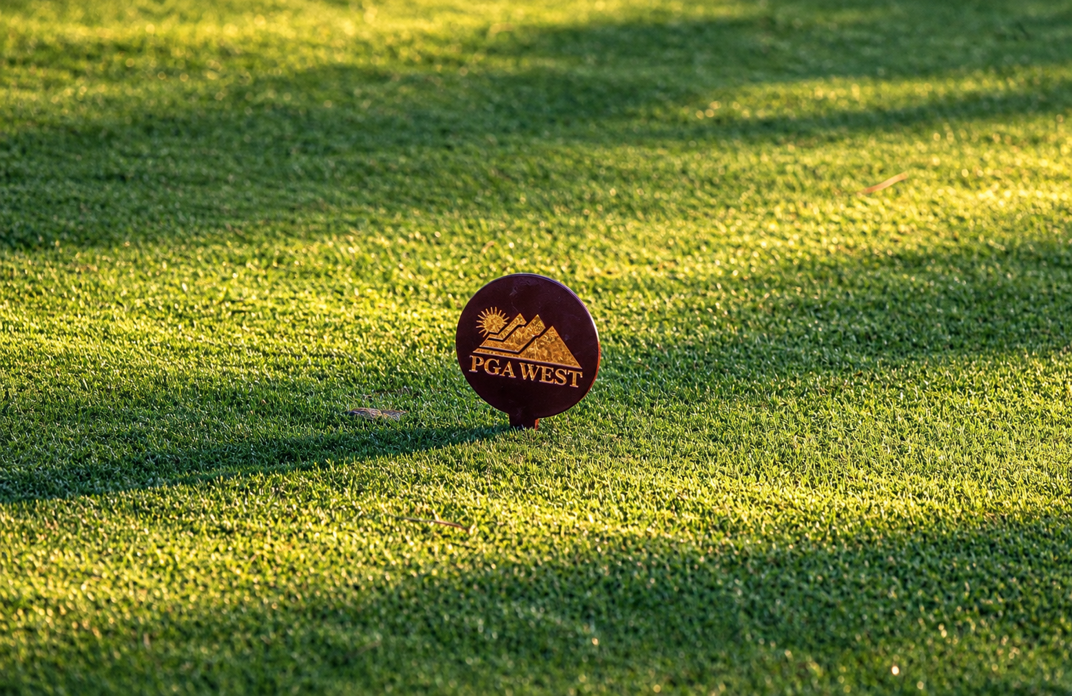PGA WEST course marker on sunlit fairway grass
