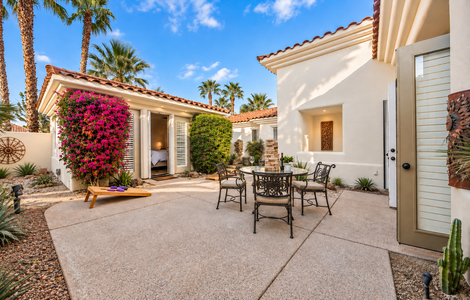 Private desert courtyard at Solmirage villa with bougainvillea, palm trees, patio dining, and Spanish architecture